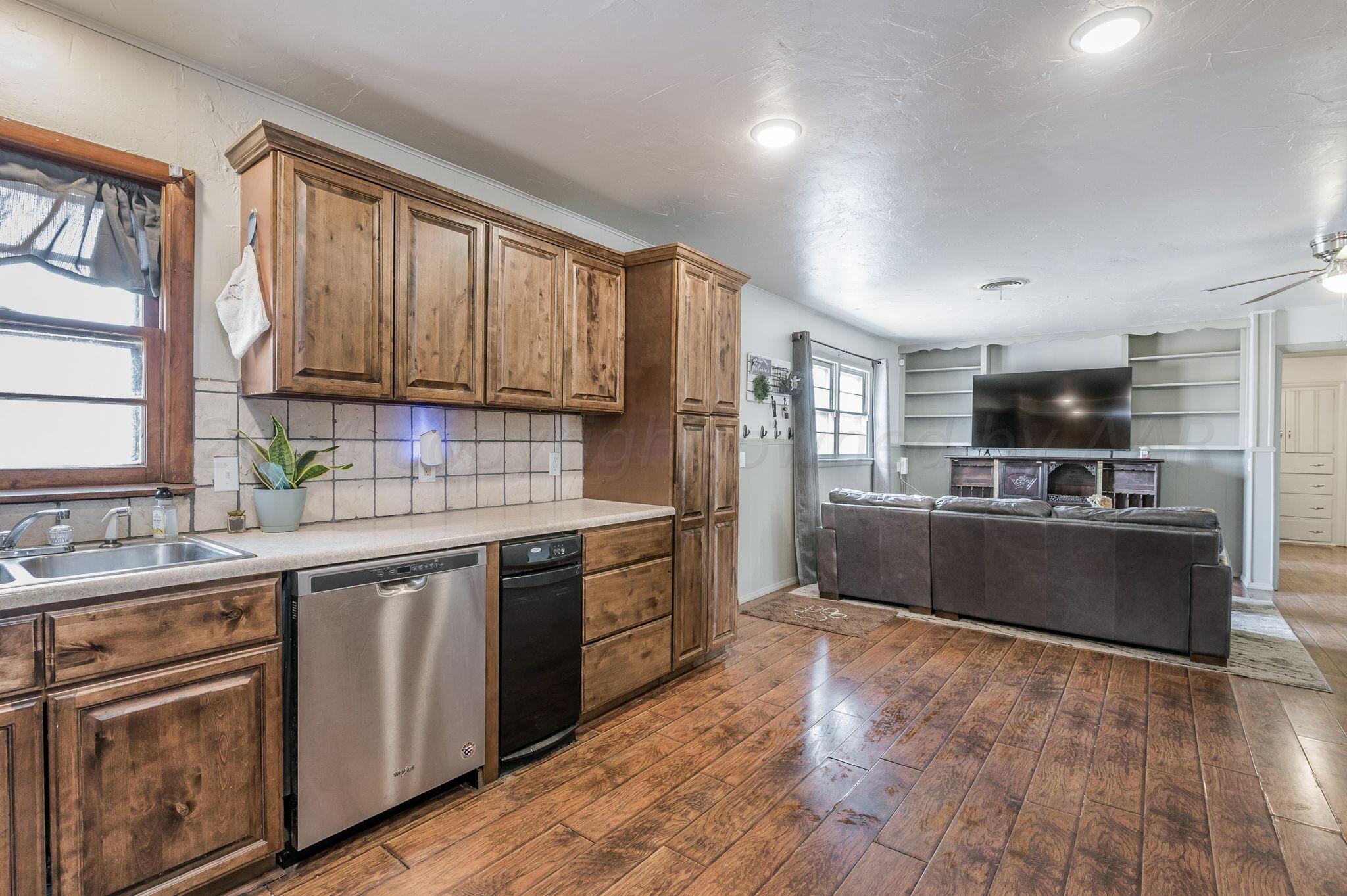 4205 South Bonham Street Amarillo, TX 79110 - Photo 9 of 24 a kitchen with stainless steel appliances granite countertop a stove top oven a sink dishwasher a refrigerator and cabinets with wooden floor