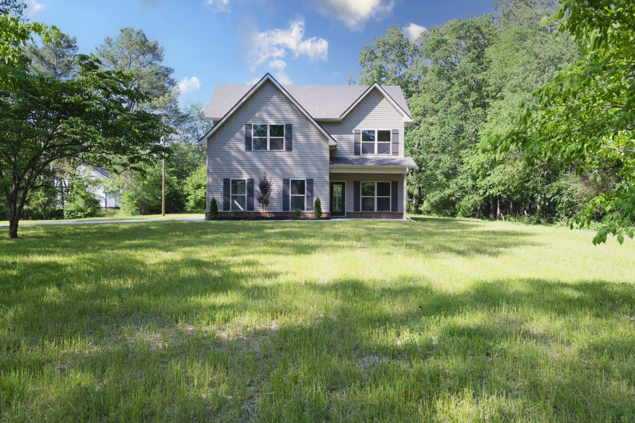 a view of a house with a big yard and large trees