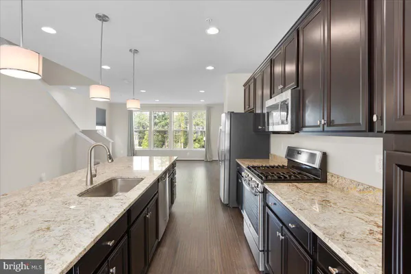 a kitchen with stainless steel appliances granite countertop sink stove top oven and refrigerator