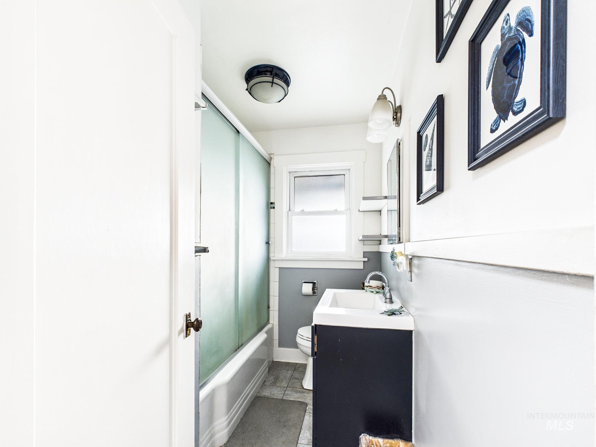 3422 6th Street Lewiston, ID 83501 - Photo 17 of 43 Bathroom featuring a frosted glass shower enclosure, a window, a dark vanity with an integrated sink, and wall-mounted lighting fixtures