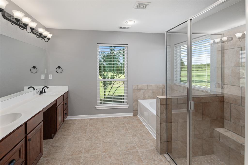 1019 Vaughan Lane Tioga, TX 76271 - Photo 7 of 40 Spacious bathroom featuring a dual vanity with dark wood cabinetry, a large built-in mirror, a glass-enclosed shower with tiled walls and a built-in bench, a separate bathtub, and tile flooring