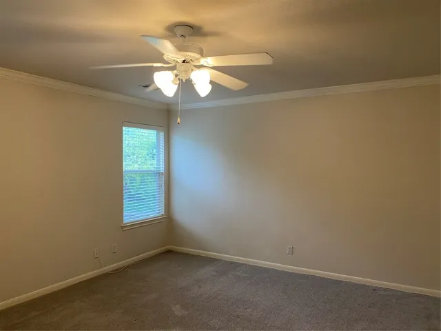 an empty room with a chandelier fan and windows
