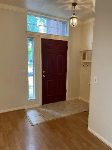 an empty room with wooden floor cabinet and windows