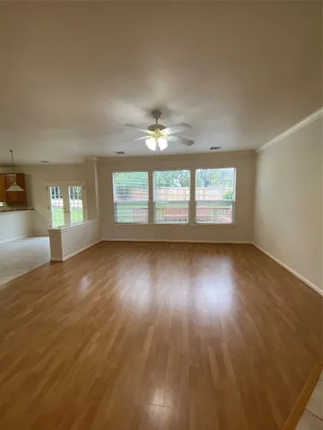 a view of an empty room with wooden floor and a window