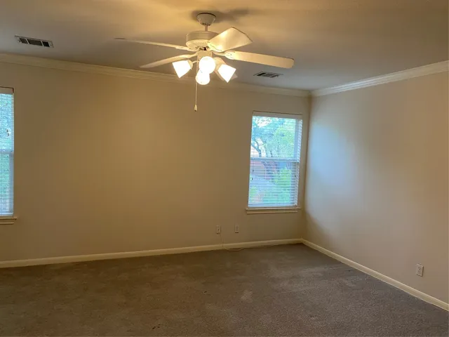 an empty room with windows and fan
