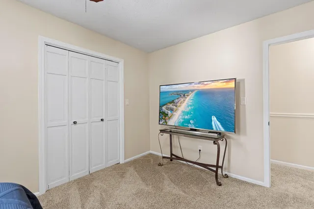 an empty room with chandelier fan and windows