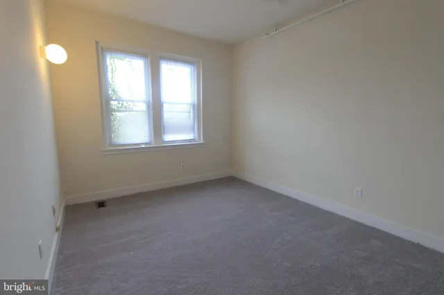 an empty room with a window and a fan