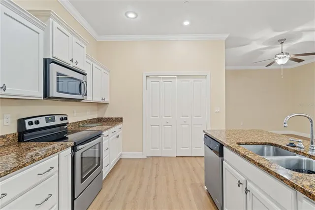 a kitchen with granite countertop a sink cabinets stainless steel appliances and a counter space