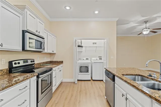 a large kitchen with stainless steel appliances a large counter top a stove a refrigerator and a sink