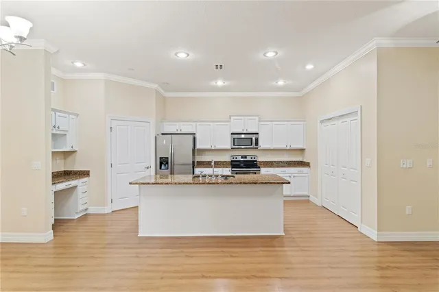 a view of kitchen with stainless steel appliances refrigerator stove and wooden floor