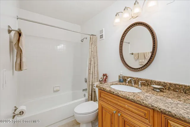 a bathroom with a granite countertop toilet a sink and a mirror
