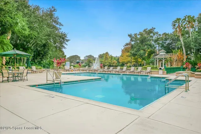 a view of swimming pool with outdoor seating and trees in the background