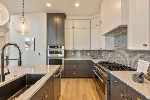 2458 West Aurora Avenue, Unit 287 Mapleton, UT 84664 - Photo 10 of 24 Kitchen featuring stainless steel appliances, decorative backsplash, light stone countertops, light wood-style flooring, and white cabinetry