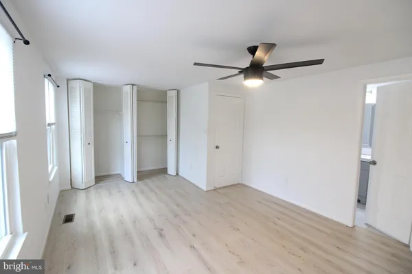 an empty room with wooden floor and fan