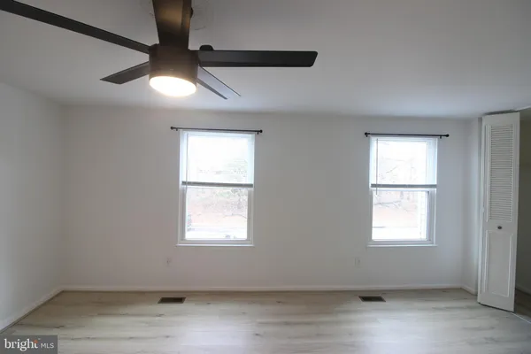 an empty room with wooden floor and windows