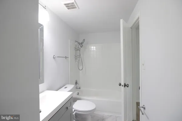 a bathroom with a granite countertop sink a toilet and shower