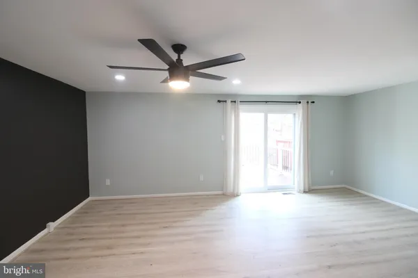 an empty room with wooden floor fan and windows
