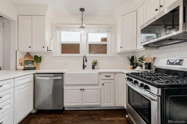 a kitchen with stainless steel appliances granite countertop white cabinets a stove a sink and dishwasher