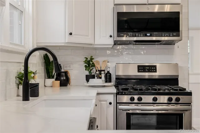 a kitchen with stainless steel appliances a stove a microwave a sink and cabinets