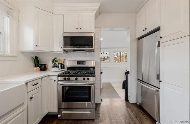 a kitchen with cabinets stainless steel appliances and wooden floor