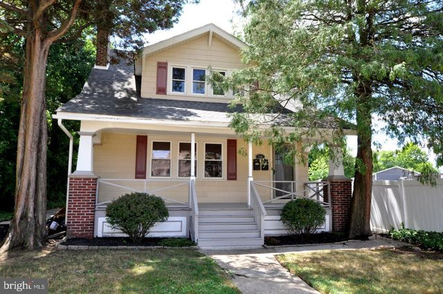 a view of a yard in front of a house with plants and large tree