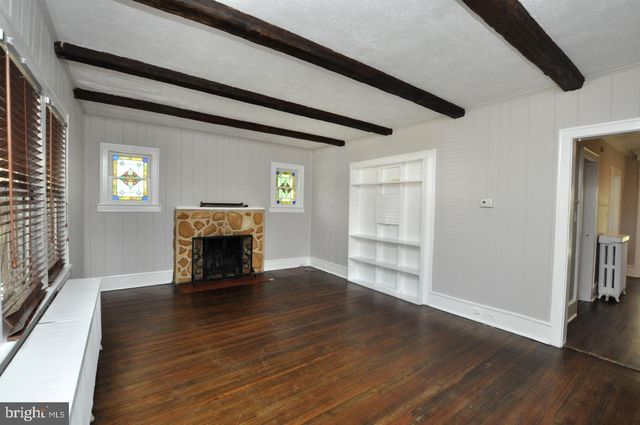 an empty room with wooden floor fireplace and windows