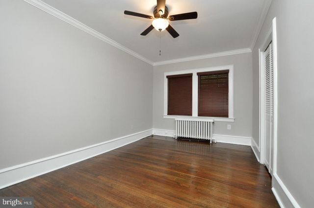 an empty room with wooden floor a ceiling fan and windows