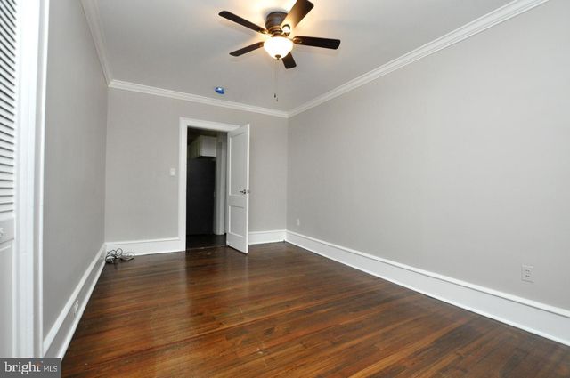 an empty room with wooden floor ceiling fan and windows