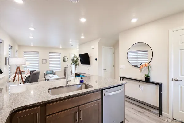 a kitchen with granite countertop kitchen island stainless steel appliances a sink stove refrigerator and cabinets