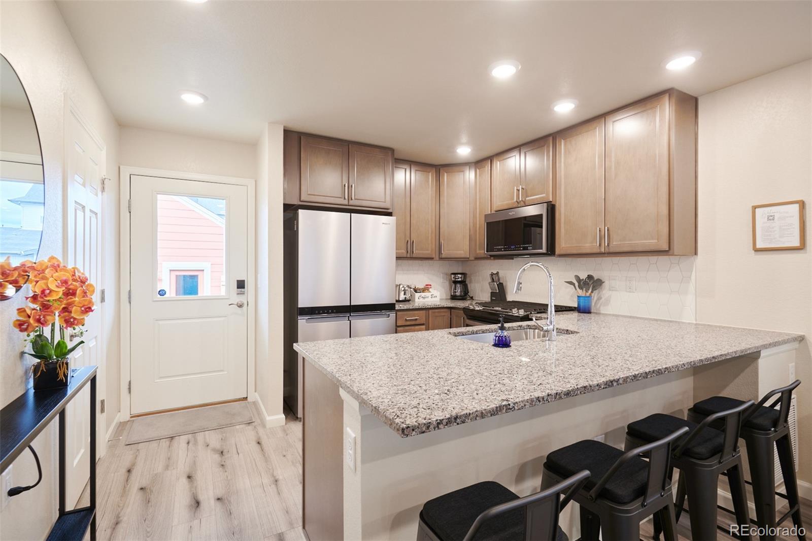 6339 North Hanover Street Denver, CO 80238 - Photo 10 of 24 a kitchen with granite countertop kitchen island stainless steel appliances a sink stove refrigerator and cabinets