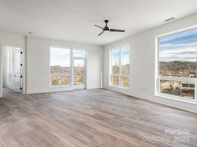 a view of an empty room with a window and wooden floor