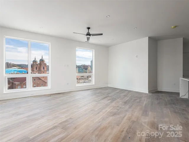 a view of an empty room with a window and wooden floor