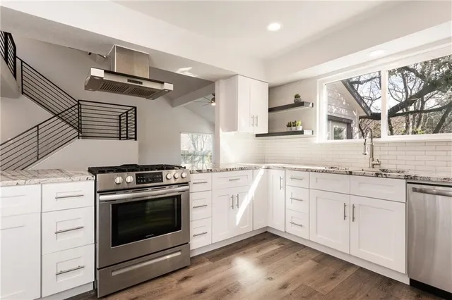 a kitchen with granite countertop wooden floor stainless steel appliances and white cabinets