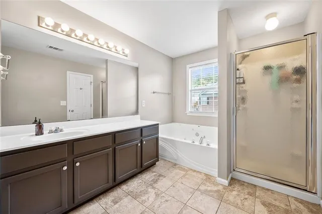 a spacious bathroom with a double vanity sink a large mirror and shower