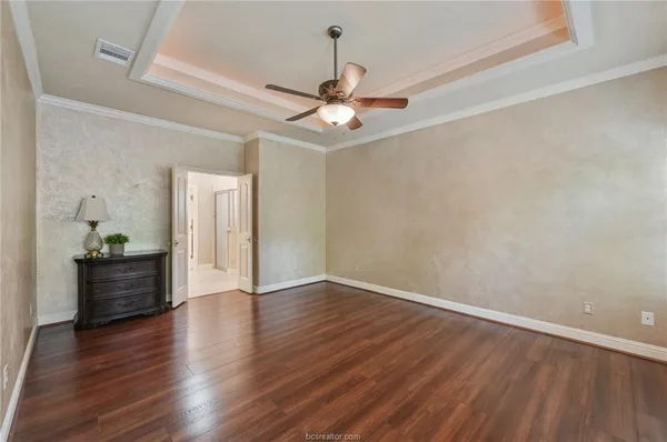 an empty room with wooden floor ceiling fan and window