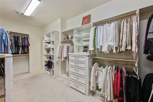 a view of walk in closet with clothes and shoes