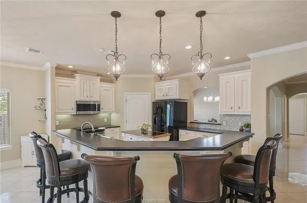 a kitchen with kitchen island a dining table chairs sink and microwave