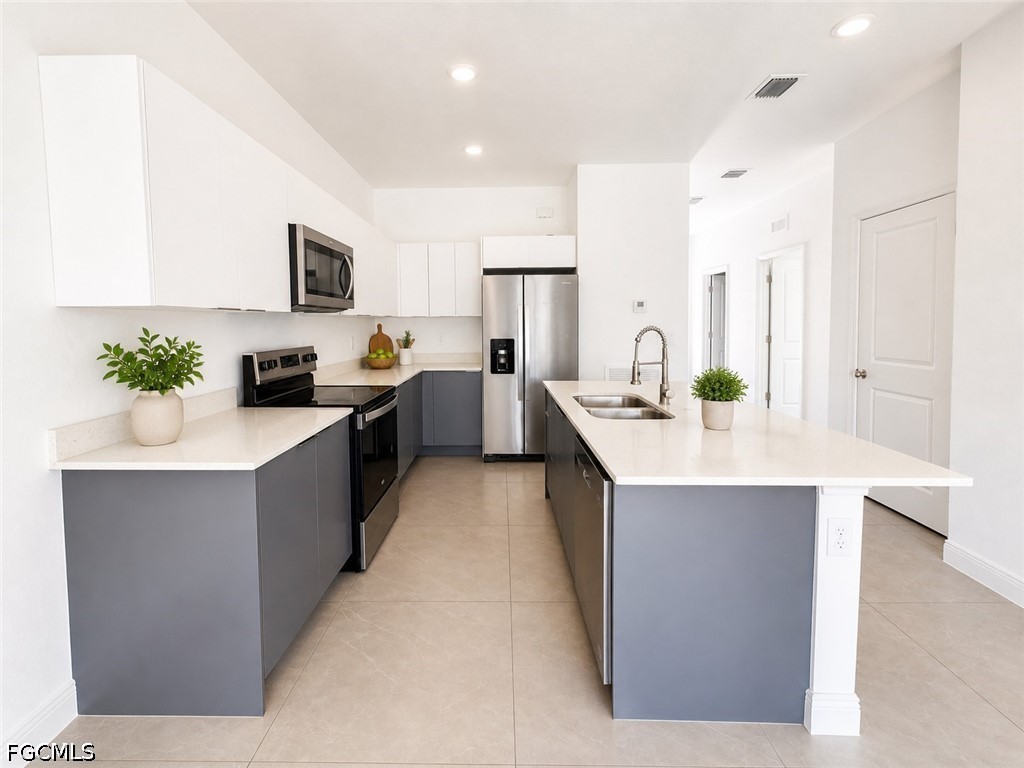 8753 Buckingham Road Lehigh Acres, FL 33971 - Photo 5 of 13 a large kitchen with stainless steel appliances a sink a counter top space and living room area