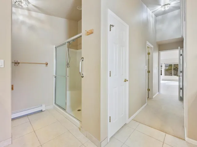 a view of a hallway with wooden floor and a bathroom