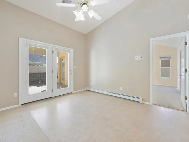 an empty room with chandelier fan and windows