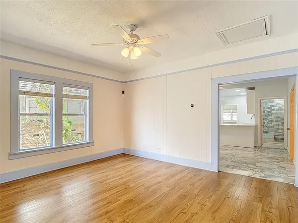 a view of an empty room with wooden floor and a window