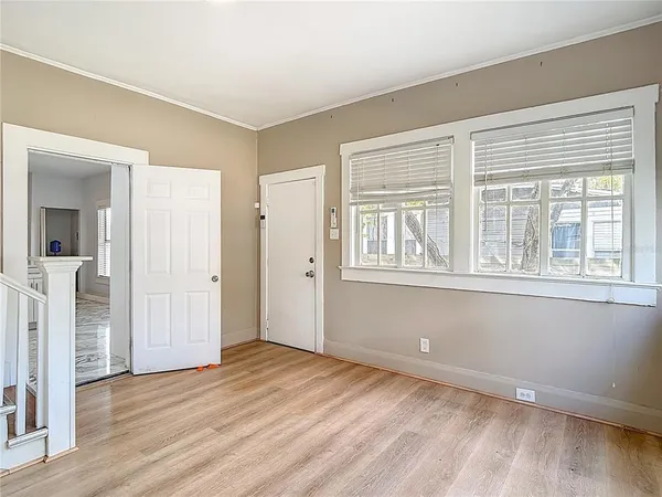 a view of an empty room with a window and wooden floor