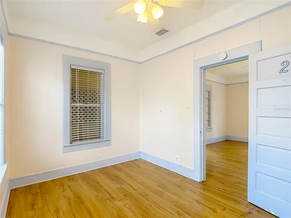 an empty room with wooden floor closet and windows