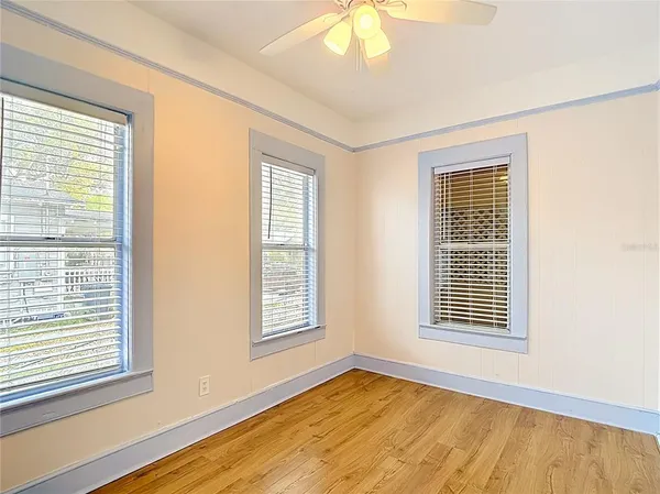 an empty room with wooden floor and windows