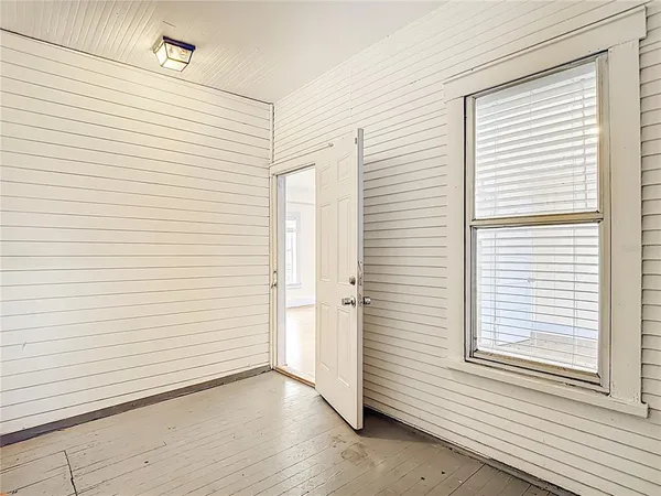 an empty room with wooden floor closet and windows