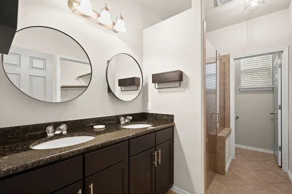 a bathroom with a granite countertop sink a mirror and a shower