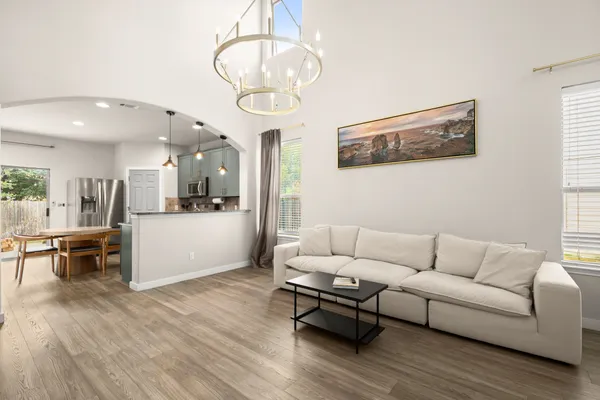 a living room with furniture kitchen view and a wooden floor