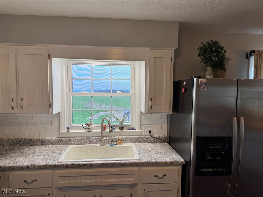 1790 Rix Mills Road New Concord, OH 43762 - Photo 10 of 28 Kitchen featuring stainless steel fridge with ice dispenser, light countertops, white cabinetry, and a sink
