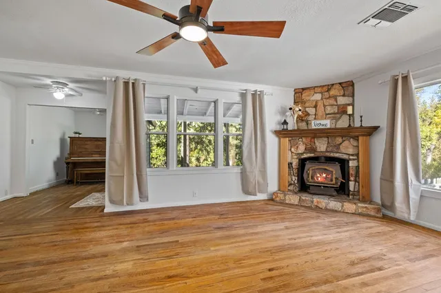 a view of a livingroom with a fireplace a ceiling fan and windows