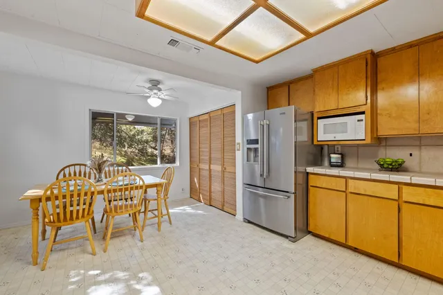 a kitchen with stainless steel appliances granite countertop a stove a refrigerator a dining table and chairs with wooden floor